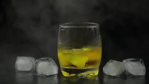 Whiskey with Ice. Adding Ice Cubes on Black Background. Glass of Rum Alcohol