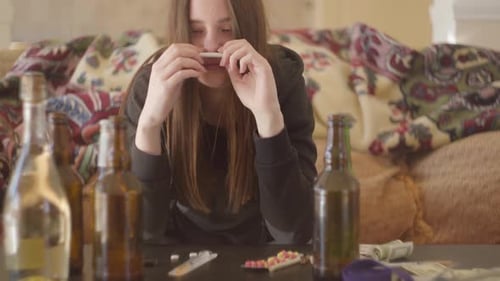 Porträt eines drogenabhängigen Mädchens, das Alkohol und Drogen konsumiert