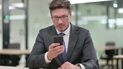 Man in Suit Uses Smartphone in Office