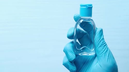 Hand in Protective Gloves Holding Hand Sanitizer