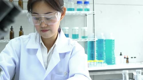 Female Scientist Inspecting Sample Under Microscope in Lab