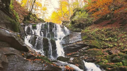 Waterfall Falling Down Mountain Slope in Autumn Forest
