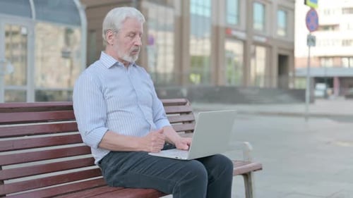 Senior Man Using Laptop on Park Bench