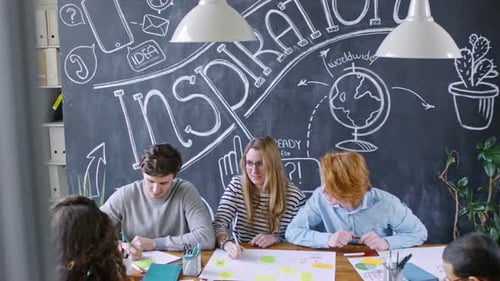 Young Creative Coworkers Discussing Project and Working at Office Desk