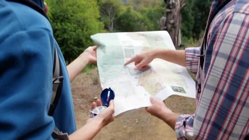 Couple Consulting Map and Compass on Forest Hike