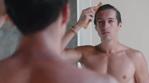 Man Grooming Hair and Face in Bathroom Mirror