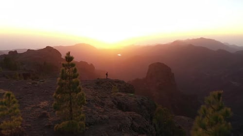 Man Standing On Rocks Watching Sunset