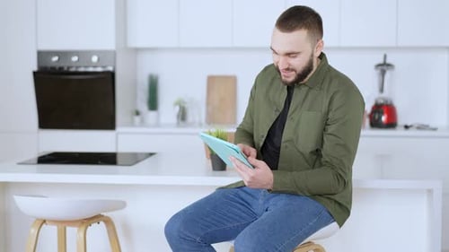 Man Using Tablet in Modern Kitchen Setting