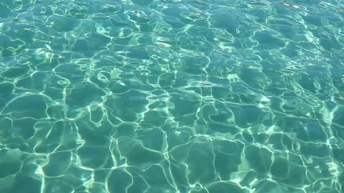Turquoise Sea with Clear Water, Sand and Small Fish Are Visible at the Bottom. Slow Motion. Close Up