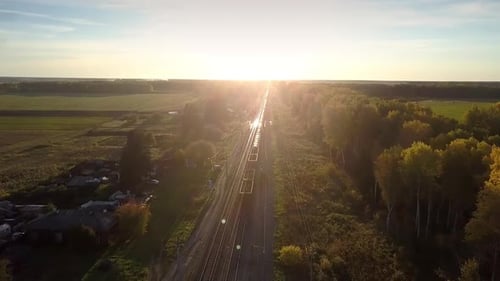 Upper View Güterzug fährt bei Sonnenuntergang durch den Wald