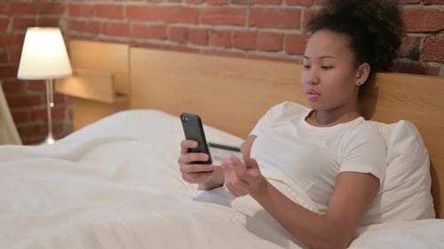 African Woman with Unsuccessful Online Payment on Smartphone in Bed