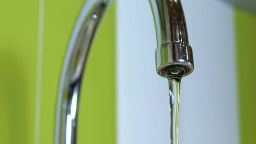 Wasser fließt aus dem Wasserhahn in eine Spüle. Zeitlupe