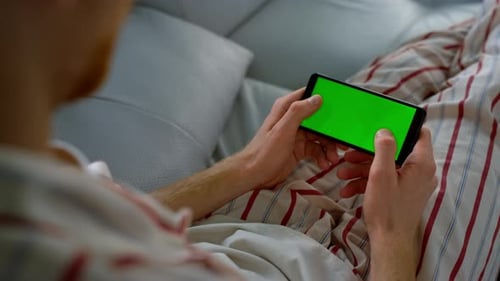 Man Typing Green Screen on Smartphone at Home