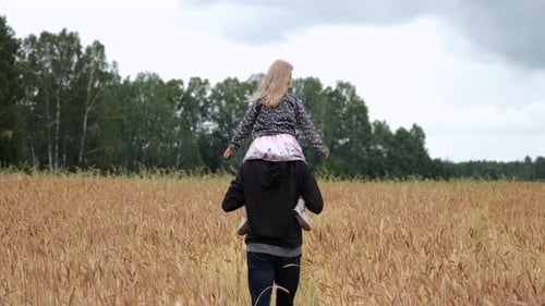 Father Giving Daughter Ride on Back in a Field