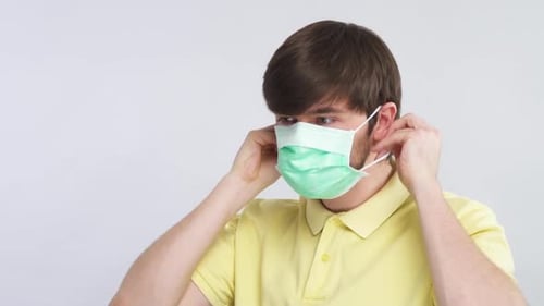 Young Adult Putting on a Protective Face Mask