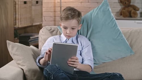 Boy Using Tablet Device on Couch at Home