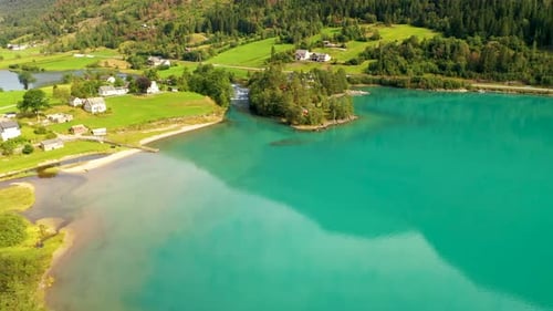cinematic aerial view of turquoise color lake with houses and holiday homes