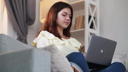 Young Woman Using Laptop on Sofa at Home