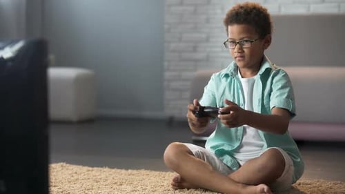 Niño masculino que se comporta agresivamente mientras pierde el juego en línea, juega en la consola