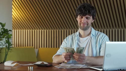 Man Counts the Money Sitting at the Table and Throws the Money Up