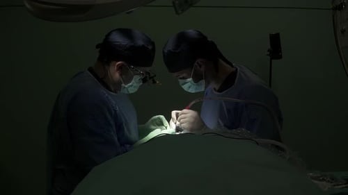 Surgeons Performing Operation in Darkly Lit Hospital Room