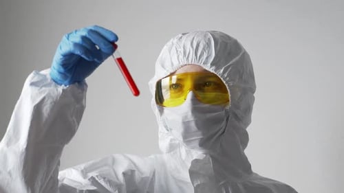 Der Arzt, eine Frau, hält ein Reagenzglas mit einem positiven Coronavirus-Test in der Hand und schaut es sich an