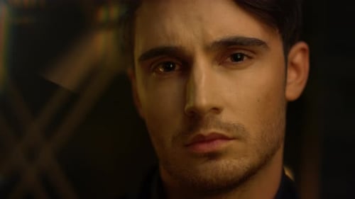 Focused Man Turning Head Indoors. Calm Male Person Looking Camera Dark Interior.