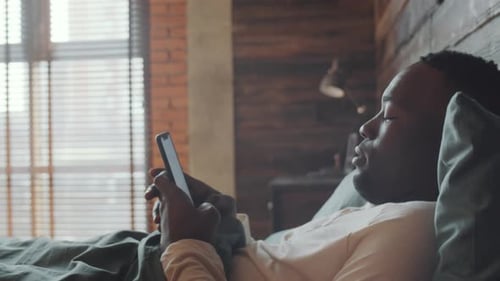 Man Using Phone While Laying in Bed