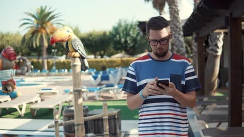 Businessman Is Reading E-mail in Smartphone, During Vacation in Hotel, Walking