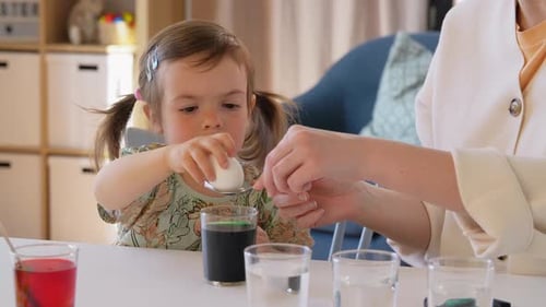 Mother with Child Dyeing Easter Eggs at Home