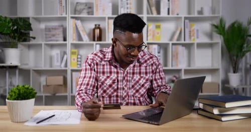 Junge Afrikaner zahlen mit Kreditkarte auf Laptop
