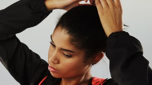 Young Woman Puts Hair in Ponytail