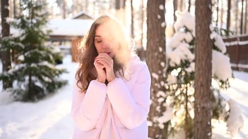 Woman Warming Hands in Snowy Winter Forest