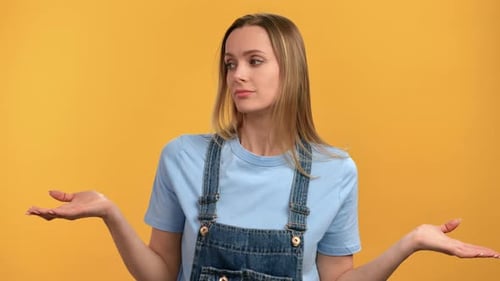 Uncertain Blonde Young Female Shrugging Shoulders Dont Know Gesture Posing Isolated on Orange Studio