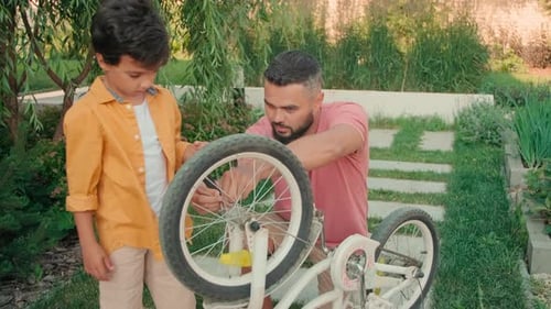 Father and Son Repairing Bike in Yard Together