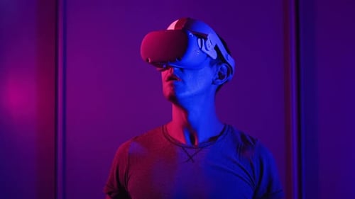 Man Using VR Headset in Neon Lit Room