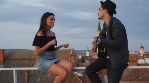 Paar spielt Gitarre auf einem Dach