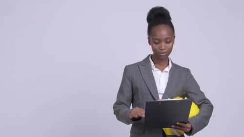 Young African Businesswoman with Hardhat Getting Angry While Reading on Clipboard