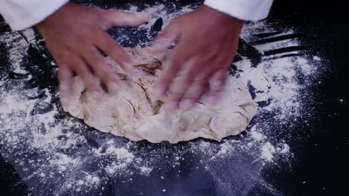 Hands Kneading Dough on Floured Surface