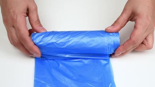 dos manos femeninas giran un rollo con bolsas de basura desechables azules