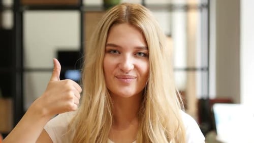 Young Woman Giving Thumbs Up Indoors