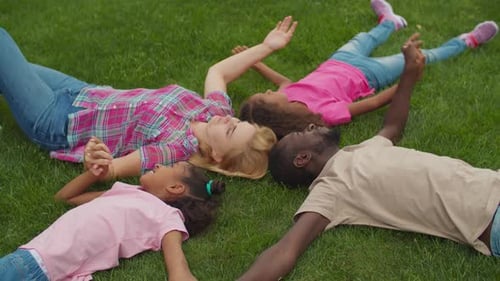 United Family Holding Hands Lying on Lawn in Circle