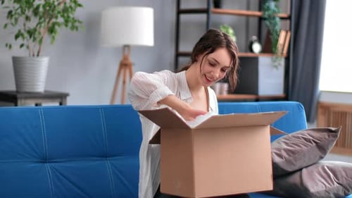 Woman Smiling as She Opens a Delivery Box Indoors