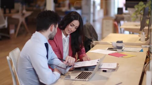 Businessman and woman sitting in office looking at contract