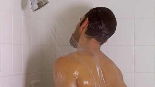 Handsome Man Showering in White Tiled Bathroom