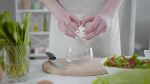 Woman Cracking Egg into Glass for Cooking