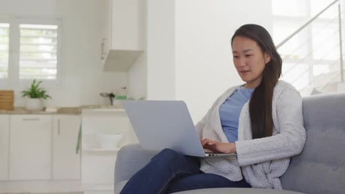 Woman Using Laptop on Couch in Modern Home