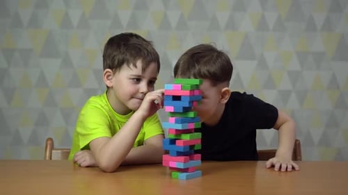 Boys Playing Tower Game at Table Indoors