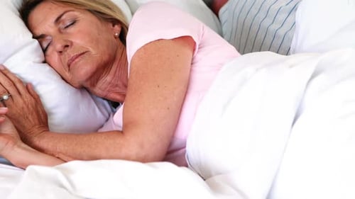 Senior couple sleeping on bed