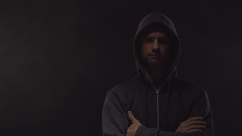 Man in Hoodie with Arms Crossed in Shadow